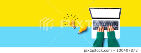Person using a laptop computer and light bulbs Person using a laptop computer and light bulbs 100407878