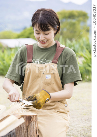 為篝火製作羽毛棒的年輕女子獨自露營圖片 100408037