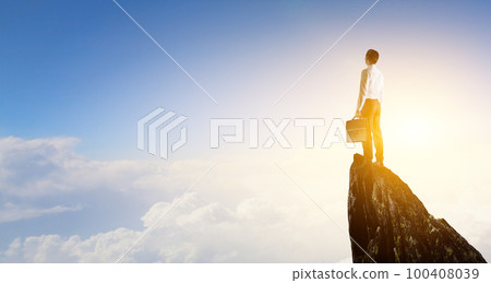 Back view of young man in suit standing on mountain top. Back view of young man in suit standing on mountain top. 100408039