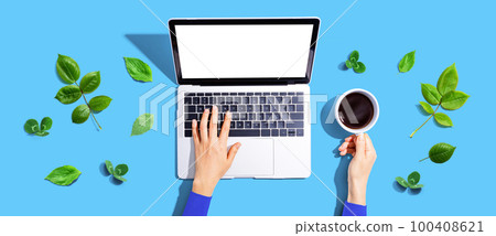Person using a laptop computer with green leaves 100408621
