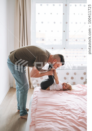 Happy father young man and baby girl little daughter having fun on bed in room at home 100411725