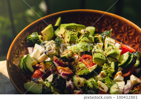 Avocado mix of vegetables salad in daytime outdoors. Fresh salad with tomatoes, avocado, lettuce onion cucumber. Healthy and detox food concept. Ketogenic diet Avocado mix of vegetables salad in daytime outdoors. Fresh salad with tomatoes, avocado, lettuce onion cucumber. Healthy and detox food concept. Ketogenic diet 100412801