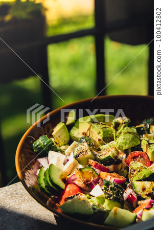 Avocado mix of vegetables salad in daytime outdoors. Fresh salad with tomatoes, avocado, lettuce onion cucumber. Healthy and detox food concept. Ketogenic diet Avocado mix of vegetables salad in daytime outdoors. Fresh salad with tomatoes, avocado, lettuce onion cucumber. Healthy and detox food concept. Ketogenic diet 100412802