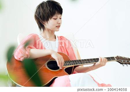 A young lady playing the guitar A young lady playing the guitar 100414038