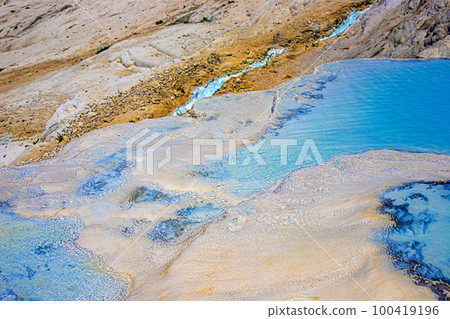 View of natural terraces in Pamukkale on a summer day. Close-up texture of limestone and water flowing over it. 100419196
