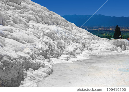 View of natural travertine pools and terraces in Pamukkale on a summer day. Texture of a white wall close-up View of natural travertine pools and terraces in Pamukkale on a summer day. Texture of a white wall close-up 100419200