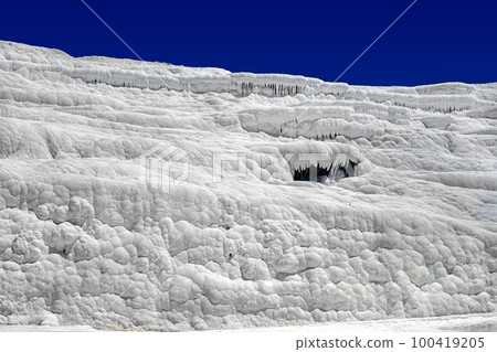 View of natural travertine pools and terraces in Pamukkale on a summer day. Texture of a white wall close-up View of natural travertine pools and terraces in Pamukkale on a summer day. Texture of a white wall close-up 100419205