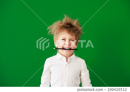 Surprised child against green chalkboard in class 100420512