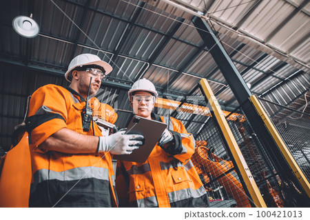 Engineer team service robot welding working in automation factory. People worker in safety suit work robotic arm software programming or replacing part in automated manufacturing industry technology. Engineer team service robot welding working in automation factory. People worker in safety suit work robotic arm software programming or replacing part in automated manufacturing industry technology. 100421013