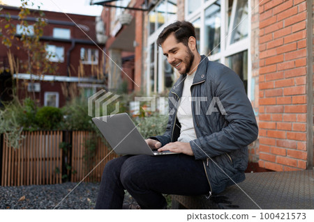 businessman holding an online meeting remotely sitting in a laptop on the street businessman holding an online meeting remotely sitting in a laptop on the street 100421573