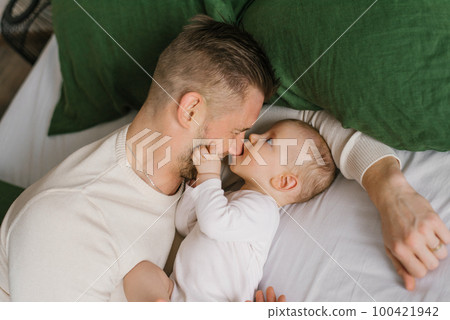 A father with a young son on the bed at home before going to bed. 100421942