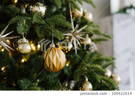 Decorated Christmas tree closeup. Golden balls and illuminated garland with flashlights. Winter holiday light decoration 100422014