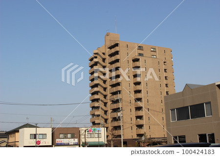 An apartment building rises in the blue sky 100424183