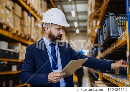 Manager in suit controlling goods in a waehouse. Manager in suit controlling goods in a waehouse. 100424324