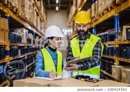 Warehouse workers checking stuff in warehouse with digital system in tablet, holding solar panel. 100424363
