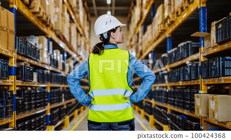 Rear view of warehouse female worker checking up stuff in a warehouse. 100424368