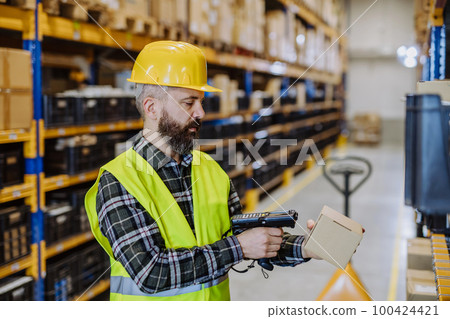Warehouse worker checking up stuff in a warehouse. Warehouse worker checking up stuff in a warehouse. 100424421