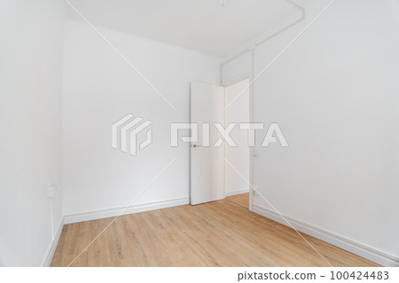 Empty white room with wooden laminate flooring and an open door in new apartment. Concept of preparing the premises for housewarming party and carrying out cosmetic repairs. Copyspace Empty white room with wooden laminate flooring and an open door in new apartment. Concept of preparing the premises for housewarming party and carrying out cosmetic repairs. Copyspace 100424483
