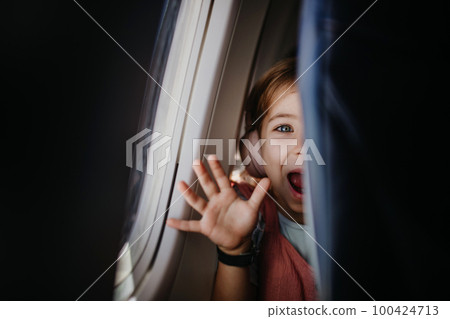Little curious girl looking through seat in airplane. 100424713