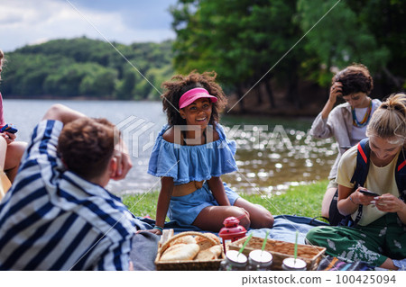 Group of multiracial young friends camping near lake and and having barbecue together. 100425094