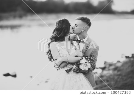 Beautifull wedding couple kissing and embracing near the shore of a mountain river with stones 100427393