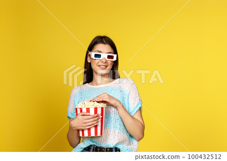 girl watching movie film, holding bucket of popcorn girl watching movie film, holding bucket of popcorn 100432512