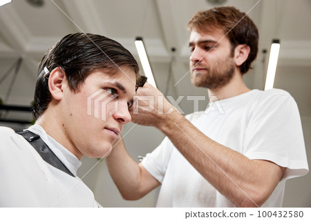 Barber talking to caucasian man while sitting in chair Barber talking to caucasian man while sitting in chair 100432580