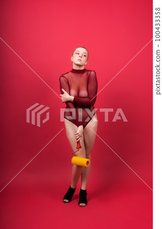 Young classic pin-up woman painting wall with paint roller Young classic pin-up woman painting wall with paint roller 100433358