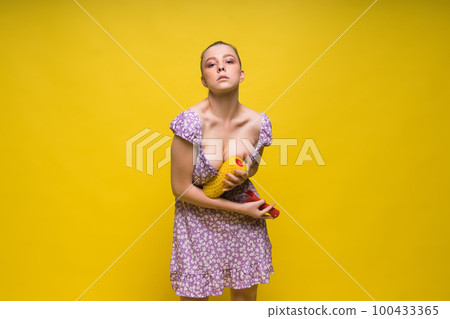 Young classic pin-up woman painting wall with paint roller 100433365