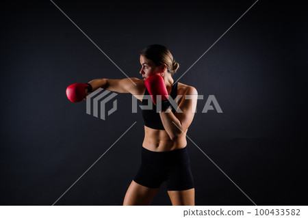 Strong sportswoman in boxing gloves prepared high kick. Isolated on white, red, yellow background 100433582