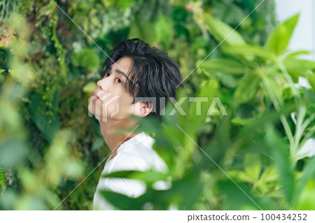 Portrait of a man surrounded by greenery, genderless makeup, men's cosmetics, skincare Portrait of a man surrounded by greenery, genderless makeup, men's cosmetics, skincare 100434252