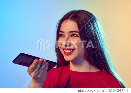 Nice-looking teen girl using cell phone over gradient blue-yellow background. Concept of communication, friendship, sales, remoute work, technology. Nice-looking teen girl using cell phone over gradient blue-yellow background. Concept of communication, friendship, sales, remoute work, technology. 100434744