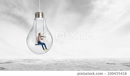 Man plays on violin sitting on light bulb Man plays on violin sitting on light bulb 100435416