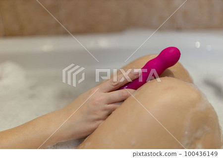 Woman in bath holding vibrator in hand  100436149