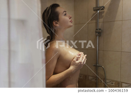 Passionate beautiful young naked woman takes a shower and covers her intimate areas. 100436159