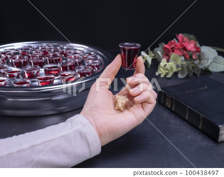 Closeup of young woman taking communion from small cups on black background Closeup of young woman taking communion from small cups on black background 100438497