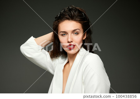 Fashionable stylish emotional woman wearing business style jacket posing over gray background. Concept of fashion, style, youth, beauty Fashionable stylish emotional woman wearing business style jacket posing over gray background. Concept of fashion, style, youth, beauty 100438856