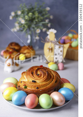 Craffin (Cruffin) with raisins and candied fruits. Traditional Easter Bread Kulich and painted eggs on a gray background. Easter Holiday. Close-up, selective focus. 100439312