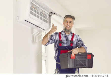 Technician man from AC service installs good modern air conditioner in the house 100443281