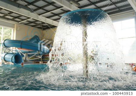 Close-up of the roof of a decorative mushroom with a waterfall of clear water on the background of a plastic slide in a water park. With space to copy. High quality photo 100443913