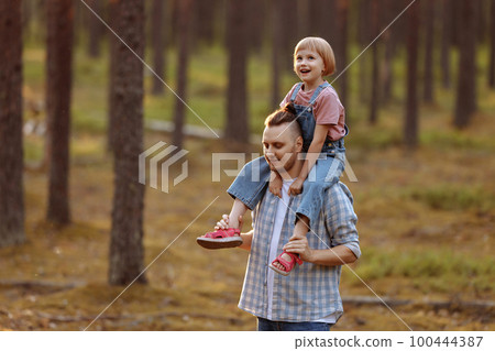 Dad and his daughter are walking along a forest road among tall pines. Dad and his daughter are walking along a forest road among tall pines. 100444387
