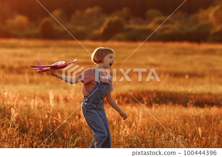 Child launches a toy plane in the field Child launches a toy plane in the field 100444396