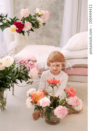 Girl 6-7 years old in a white dress holds a flower Girl 6-7 years old in a white dress holds a flower 100444411