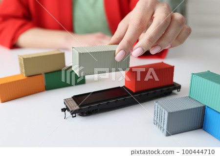 Manager's hand arranges cargo containers and railcars on table. 100444710
