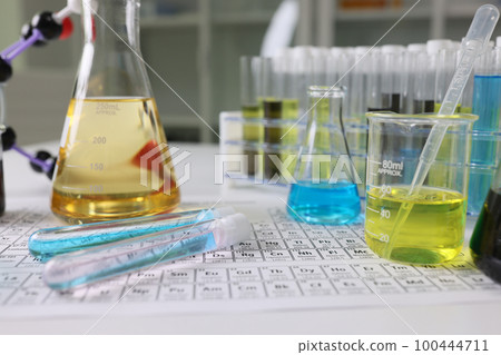 Research laboratory glassware with reagents on periodic table of chemical elements. 100444711
