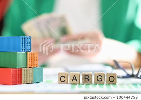 Stack of several containers, cubes with the word cargo and glasses on financial data documents. Stack of several containers, cubes with the word cargo and glasses on financial data documents. 100444759