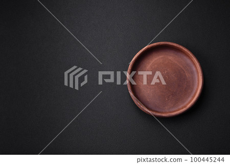 Empty brown colored ceramic plate on dark concrete background Empty brown colored ceramic plate on dark concrete background 100445244