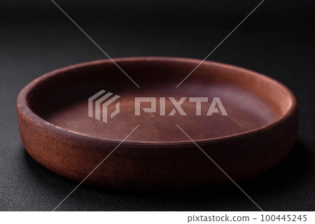 Empty brown colored ceramic plate on dark concrete background Empty brown colored ceramic plate on dark concrete background 100445245