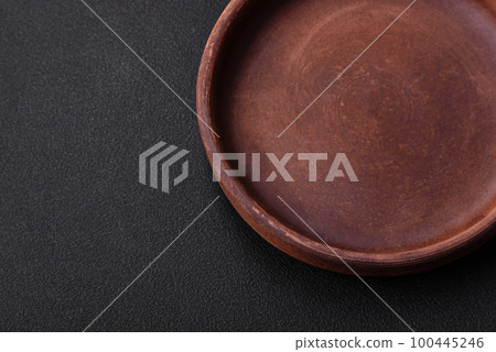 Empty brown colored ceramic plate on dark concrete background Empty brown colored ceramic plate on dark concrete background 100445246