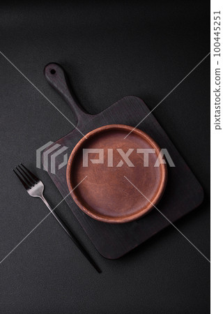 Empty brown colored ceramic plate on dark concrete background 100445251